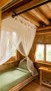 a bed in a room with a mosquito net at Elang Hillside Bamboo Villas in Labuan Bajo