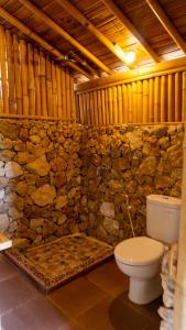 a bathroom with a toilet and a stone wall at Elang Hillside Bamboo Villas in Labuan Bajo