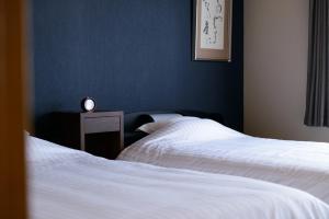Duas camas num quarto com um relógio numa mesa de cabeceira em Shiki Homes HIKARI em Quioto