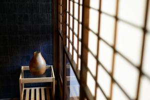 un jarrón sentado en una mesa junto a una ventana en Shiki Homes HIKARI en Kioto