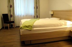 ein Schlafzimmer mit einem Bett, einem Stuhl und einem Fenster in der Unterkunft Landpension Wachtkopf Ferienwohnungen in Vaihingen an der Enz