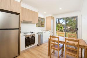 Callala BayNautilus Pet Friendly 5 Mins Walk to Bay的厨房配有桌子、冰箱和桌椅