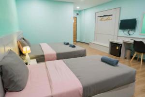 a room with two beds and a desk and a television at Sritrang Residence in Ban Khlong Wa