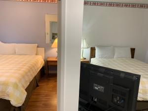 1 dormitorio con 2 camas y TV. en Swiss Sunset Inn, en Penticton