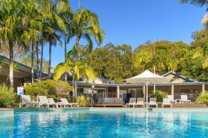 a house with a swimming pool and palm trees at NRMA Angourie Resort, Yamba in Yamba