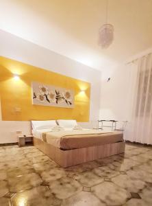 1 dormitorio con cama y pared amarilla en Le Terre di Sicilia, en Terrasini
