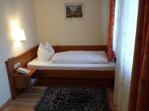 Cama pequeña en habitación con lámpara y alfombra en Hotel am Exerzierplatz en Mannheim