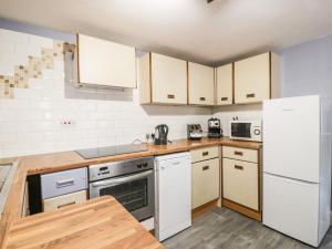 a kitchen with white appliances and wooden cabinets at Portland in Brodick