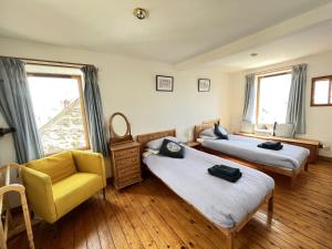 a bedroom with two beds and a yellow chair at Tall Ship - Three-bedroom coastal house with sea views in Anstruther