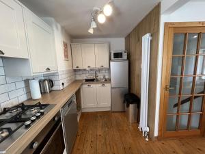 a kitchen with white cabinets and a refrigerator at Tall Ship - Three-bedroom coastal house with sea views in Anstruther