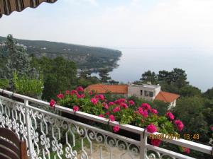 a balcony with pink flowers and a view of the water at kutlesa 2 in Opatija