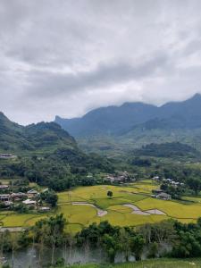 ein Dorf auf einem Feld mit Bergen im Hintergrund in der Unterkunft Ha Giang Safari Hostel & Motorbikes in Ha Giang