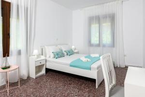 a white bedroom with a bed and a window at Whitegold Apartments Panagia in Panagia