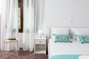 a white bedroom with two beds and a side table at Whitegold Apartments Panagia in Panagia