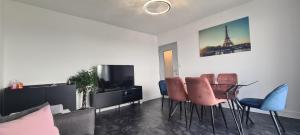 a living room with a table and chairs and a tv at Appartement 65m² Paris - DisneyLand - RER A in Noisy-le-Grand
