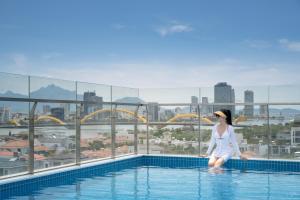 Santori Hotel And Spa في دا نانغ: امرأة تقف على حافة حمام السباحة