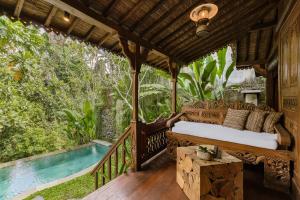 a bedroom on a deck with a bed and a pool at Bubu Mesari Ubud Villa in Ubud