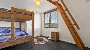 a bedroom with bunk beds and a ladder at Shamrock 3 in Mount Hotham