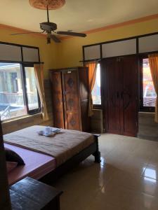 a bedroom with a bed and a fan and windows at Depa House in Ubud