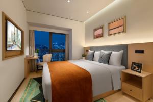 a bedroom with a large white bed and a window at Citadines Gaoxin Chengdu in Chengdu