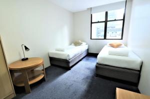 Zimmer mit 2 Betten, einem Tisch und einem Fenster in der Unterkunft Siesta Sydney in Sydney