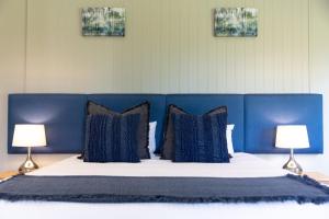 a bed with blue headboard with pillows and two lamps at The Grange On Hermitage in Pokolbin