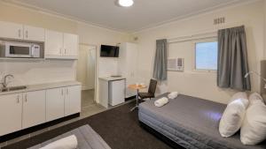 a small bedroom with a bed and a kitchen at Cowra Motor Inn in Cowra