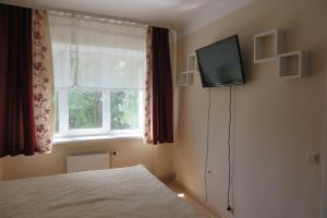 a bedroom with a bed and a television on the wall at WILLOW apartamenti in Liepāja