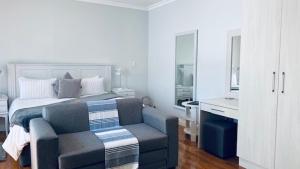 - une chambre avec un lit, un canapé et une chaise dans l'établissement On the Bay, à Port Elizabeth