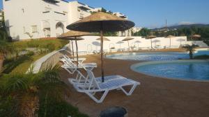 een paar stoelen en een parasol naast een zwembad bij Magnifique Villa Al Cudia Smir vue Mer Fnideq / Mdiq in Fnidek