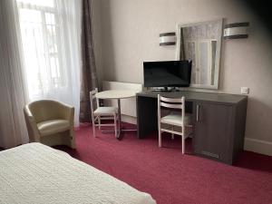 a hotel room with a desk with a television and chairs at Hôtel de Paris in Châtel-Guyon