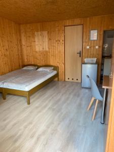 a bedroom with a bed and a refrigerator and a chair at Orle Gniazdo domki in Stegna
