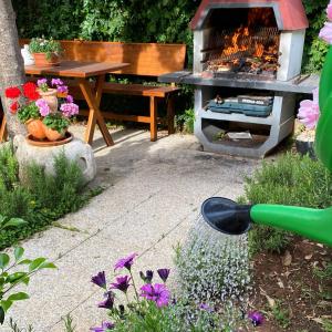 a garden with a grill and a table and flowers at Guest House Vila Micika Dubrovnik in Dubrovnik