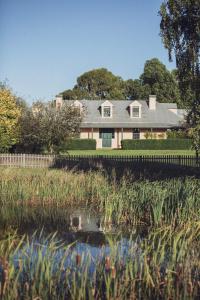 a house with a fence next to a pond at CLAYFIELD HOMESTEAD - rustic country accommodation in Bishopsbourne