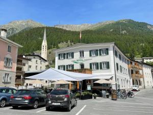 a large white building with cars parked in a parking lot at Hotel Spöl Restaurant in Zernez