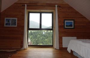ein Schlafzimmer mit einem großen Fenster in einem Holzhaus in der Unterkunft Bel Air en Chartreuse in Saint-Pierre-de-Chartreuse