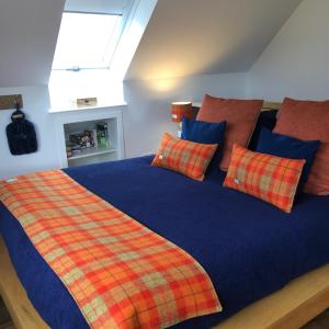 a bedroom with a bed with a plaid blanket and pillows at Drovers Studio Apartment in Tomatin