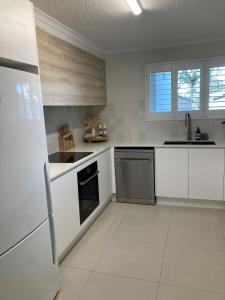 a white kitchen with white cabinets and a dishwasher at Munna Beach Apartments in Noosaville