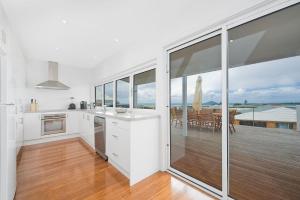 una cucina con armadi bianchi e una grande finestra in vetro di Seaview Apollo Escape - BYO Linen a Apollo Bay