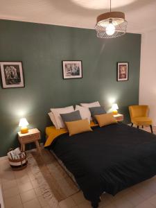 a bedroom with a large bed and a green wall at La petite Arlésienne - Charmante maison de ville in Arles