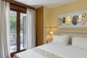 a bedroom with a white bed and a window at Vouliagmeni's Elegance by Acropolis Suites in Athens