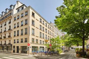 - un grand bâtiment blanc dans une rue de la ville avec des chaises dans l'établissement Le Petit Borda, à Paris