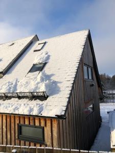 a wooden barn with snow on the roof at Drovers Studio Apartment in Tomatin