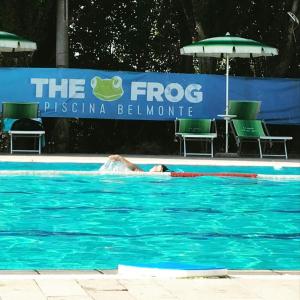 eine Person, die in einem Pool mit Sonnenschirm schwimmt in der Unterkunft Ca' di Lena in Belmonte in Sabina