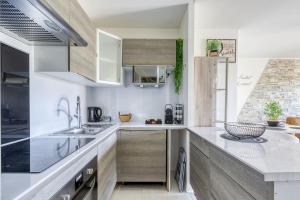 una cocina con encimeras blancas y armarios de madera en L'éclat Verdoyant de Noisy - Jardin, en Noisy-le-Grand