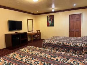 a hotel room with two beds and a flat screen tv at Welcome Inn in Inglewood