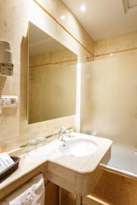 a bathroom with a sink and a mirror and a tub at Hotel Dauro Premier in Granada