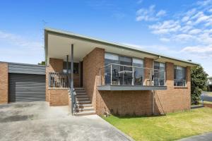 a brick house with a balcony and a garage at Schram - BYO Linen in Apollo Bay