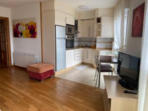 a kitchen with white cabinets and a table and a television at Jardín de Boiro in Boiro