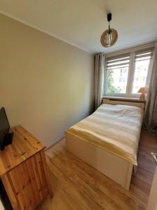 a bedroom with a bed and a window and a table at Apartament 5 minut spacerem od plaży in Giżycko